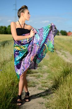 Female model from Poland, outdoor photo. Charming girl holds colorful skirt in her hand.