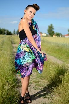 Female model from Poland, outdoor photo. Charming girl holds colorful skirt in her hand.