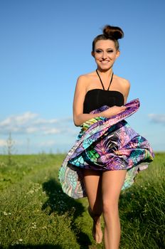 Young female model from Poland surrounded by green fields of grains. Girl portrait with colorful skirt.