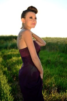 Female model outdoor portrait during sunset. Warm sunlight. Polish girl wearing dark red dress, smiling gently.