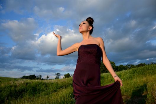 Beautiful girl from Poland, outdoor portrait. Young female model posing with different hands gesture. Blue sky with single clouds and green fields as background.