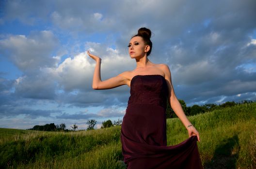 Beautiful girl from Poland, outdoor portrait. Young female model posing with different hands gesture. Blue sky with single clouds and green fields as background.