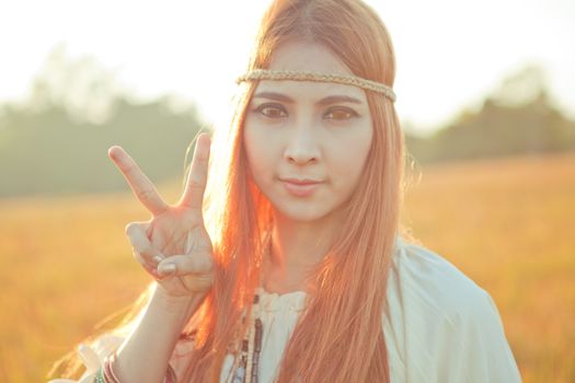Hippie girl with peace signs in golden field