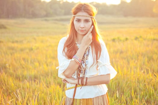 Hippie woman posing in golden field on sunset