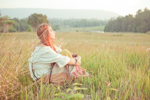 Country hippie girl sitting at golden field