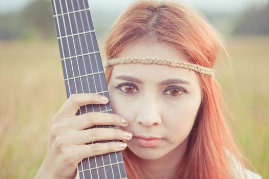 Close up of Pretty country hippie girl with guitar on grass