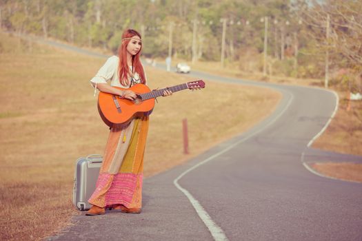 Hippie woman playing music and dancing on the country road