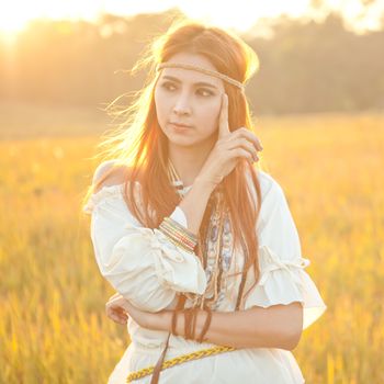 Hippie woman posing in golden field on sunset