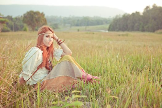 Country hippie girl sitting at golden field