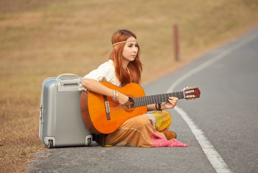 Hippie woman playing music on the country road