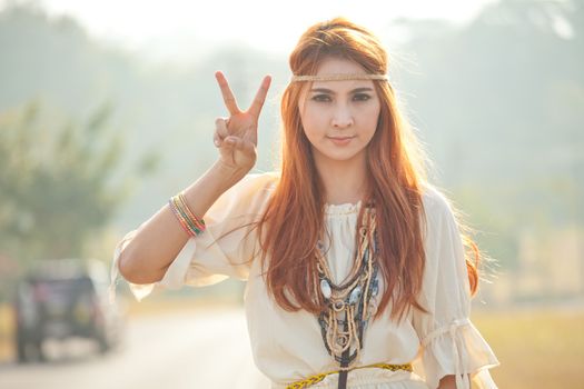 Hippie girl with peace signs in golden field