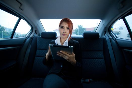 Young business asian woman inside her car using a tablet