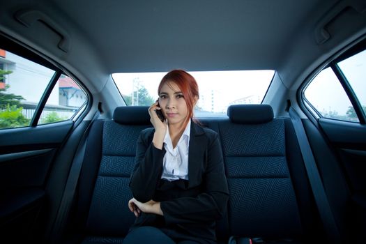 Beautiful young business asian woman using a smart phone in a car