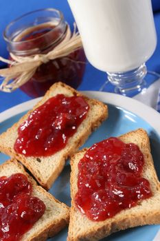 Homemade breakfast, toast with jam, a glass of milk and a jar of jam