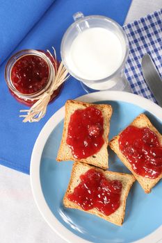 Homemade breakfast, toast with jam, a glass of milk and a jar of jam