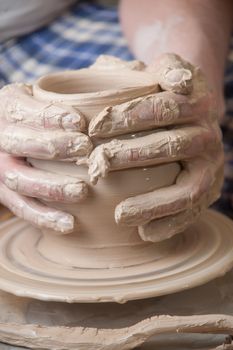 Hands of a potter, creating an earthen jar on the circle