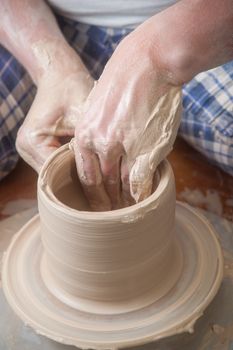 Hands of a potter, creating an earthen jar on the circle