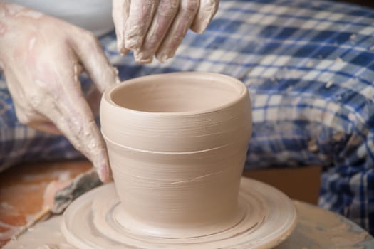 Hands of a potter, creating an earthen jar on the circle