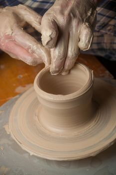 Hands of a potter, creating an earthen jar on the circle