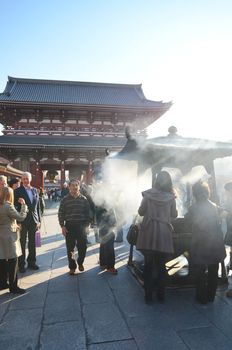 TOKYO, JAPAN - NOVEMBER 21: Buddhists gather around a fire to light incense and pray at Sensoji Temple on November 21, 2013 in Tokyo, Japan.