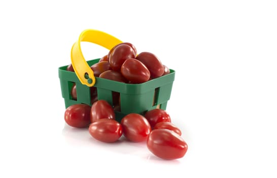 green shopping basket with red tomatoes isolated on white