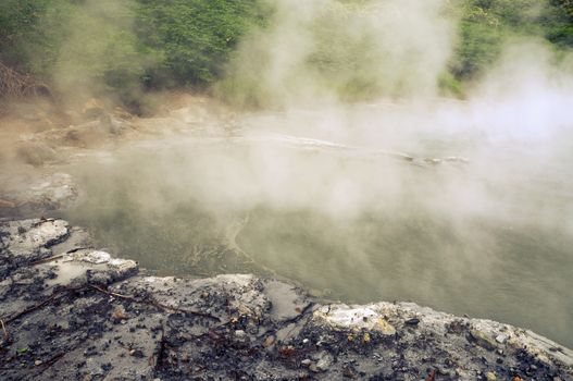 natural hot basin with steam over it in volcanic area of Hokkaido island