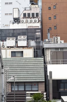 vertical city scene full of air conditioner units on the backside of modern Tokyo buildings