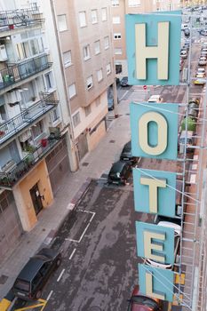 vertical hotel letters fixed on the building with real city street on backward