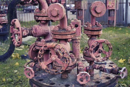 complicated rusty industrial pipe structure with many different pipe-wheels; focus on front wheel