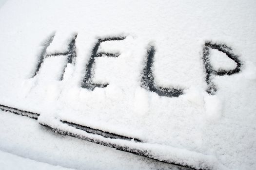 Help word written on front car window covered by heavy wet snow