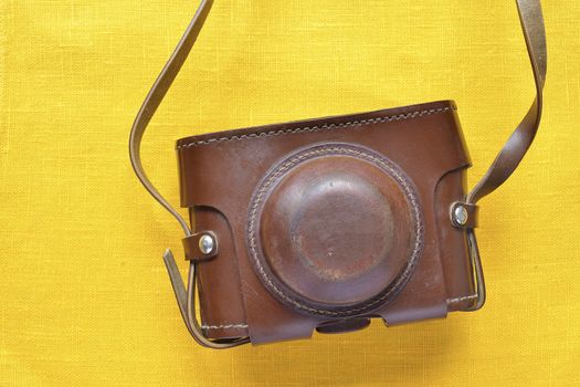 vintage photo camera  leather case over yellow background; focus on case surface