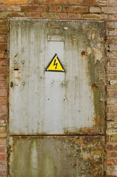 small iron door with yellow warning sign of danger