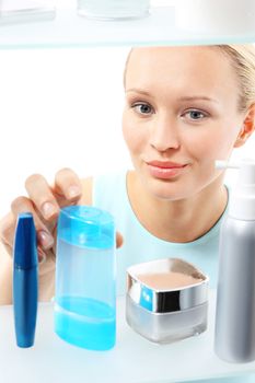 A woman stands at the client shelf and selects cosmetics..