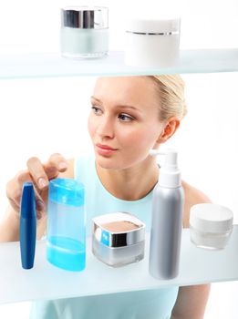 A woman stands at the client shelf and selects cosmetics..