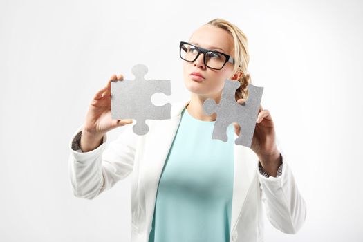 Attractive woman in business outfit adjusts the pieces of the puzzle