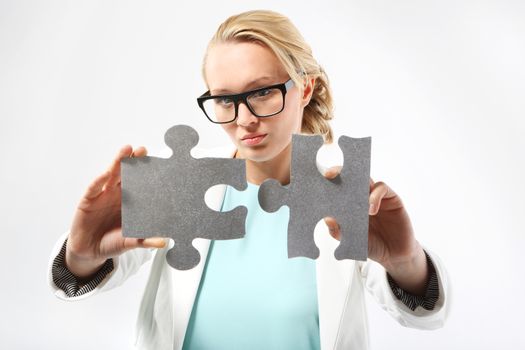 Attractive woman in business outfit adjusts the pieces of the puzzle