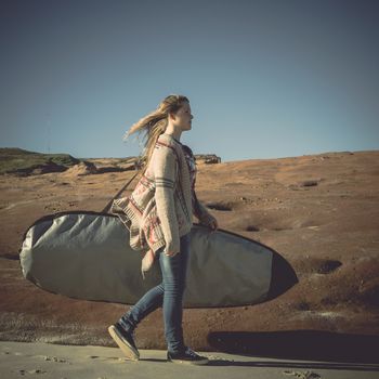 Teenage girl arrive to the beach with her surfboard