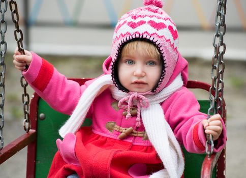 Cute Little girl on the playground ride on a swing