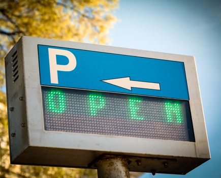 Open... green parking  sign in front a parking lot