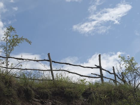 Sky, clouds and old wooden fence near the road