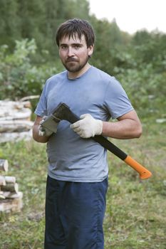 Young lumberman in a forest with an axe in his hands 