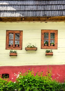 Detail of colorful windows with flowers on old traditional house, Vlkolinec village, Slovakia