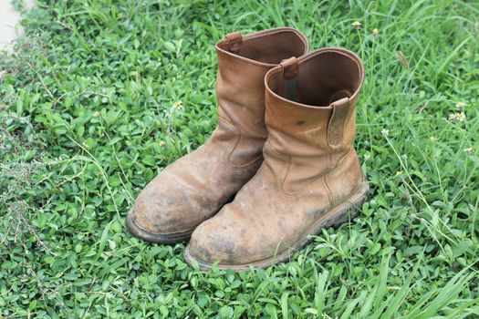 Old brown work boots on green grass