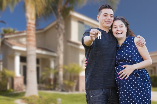 Happy Hispanic Couple In Front of New Home Showing Off Their House Keys.