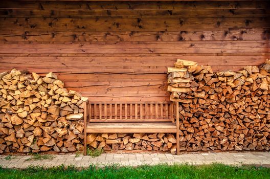 Detail of empty wooden bench with pile of firewood