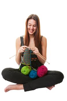 A young woman knitting a stripped scarf using three different colors of yarn.  Shot on white Background.