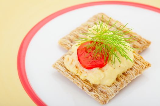 Rosemary and olive oil crackers topped with creamy deviled egg filling, baby tomato, a dash of paprika, and finished with a garnish of fine, fresh fennel.