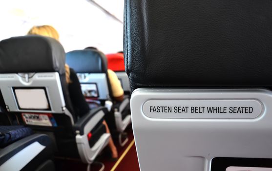 airplane seat with fasten seat belt while seated text