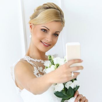 Wedding. Attractive bride with beautiful bouquet and mobile phone