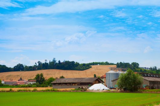 Farm with silos under blue cloudy sky